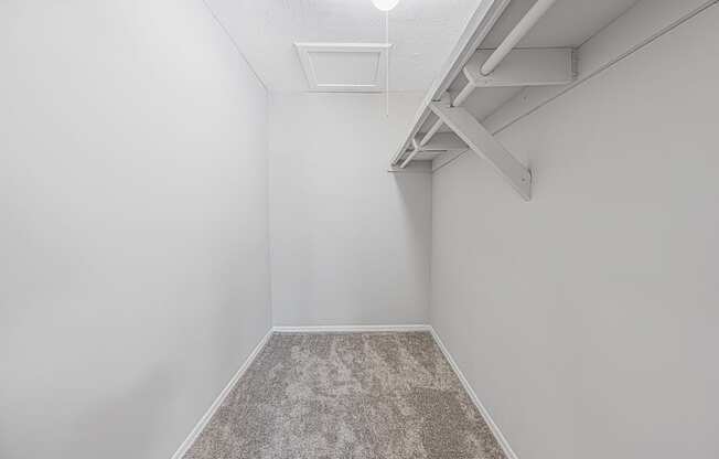 an empty room with white walls and a carpeted floor and a white ceiling fan