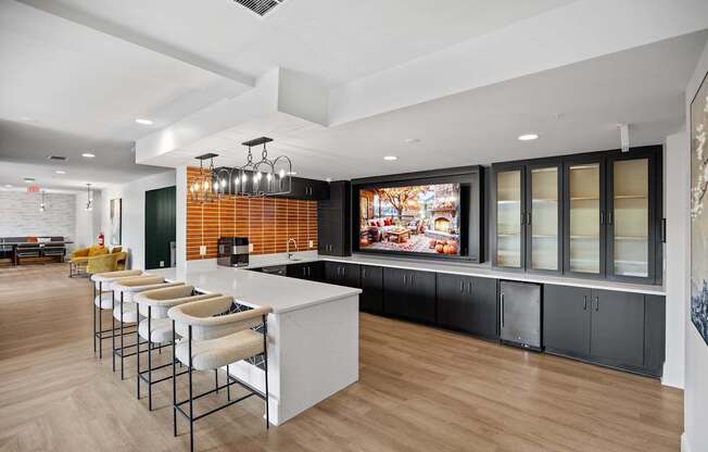 A modern kitchen with a long bar and stools.