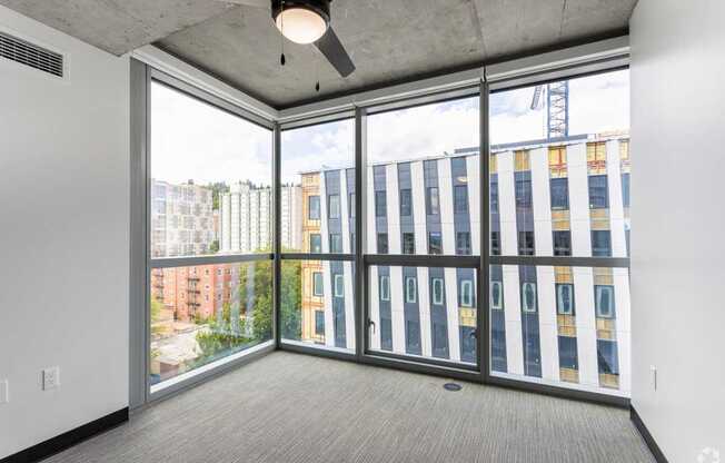 A room with a ceiling fan and a view of a construction site outside the window.