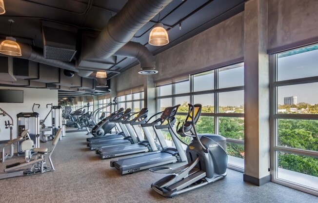 The fitness center at our apartments in Miami, featuring treadmills, elliptical bikes, weights, exercise machines, and more.