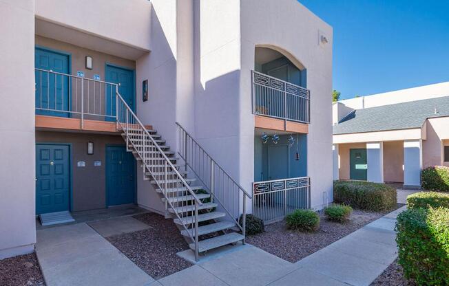 A building with a blue door and a staircase leading to a balcony.