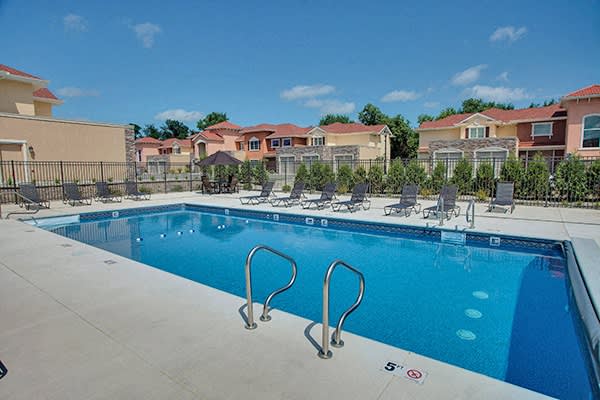 a swimming pool with lounge chairs around it and apartments in the background at The Residences at Toscana Park, Granger