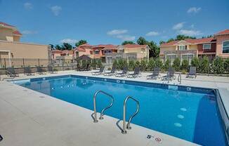 a swimming pool with lounge chairs around it and apartments in the background at The Residences at Toscana Park, Granger