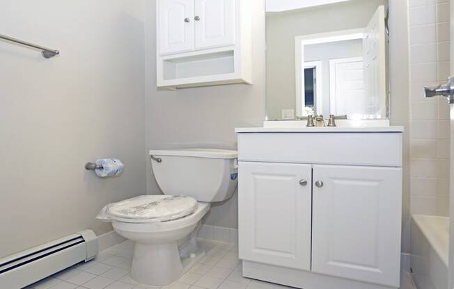 A white toilet sits in a bathroom next to a white cabinet.