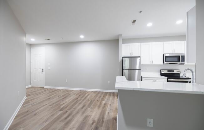 an open kitchen and living room with white walls and wood flooring