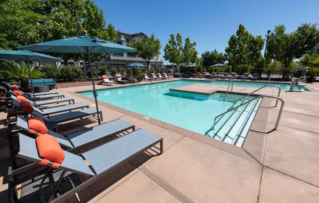 expansive pool with surrounding lounge chairs and umbrellas