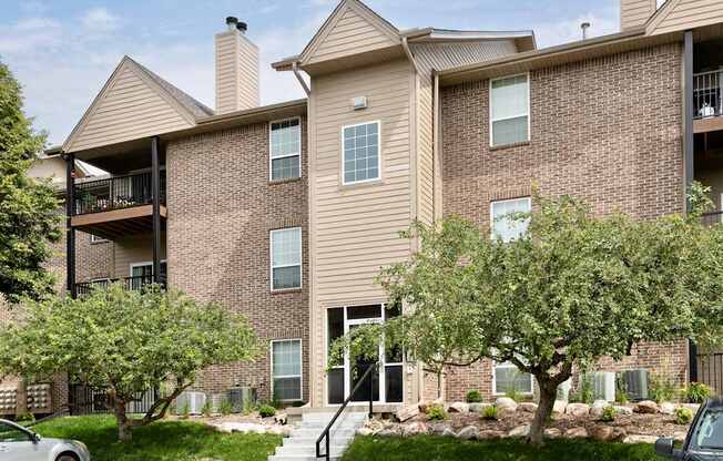 A large brick apartment building with a tree in front.