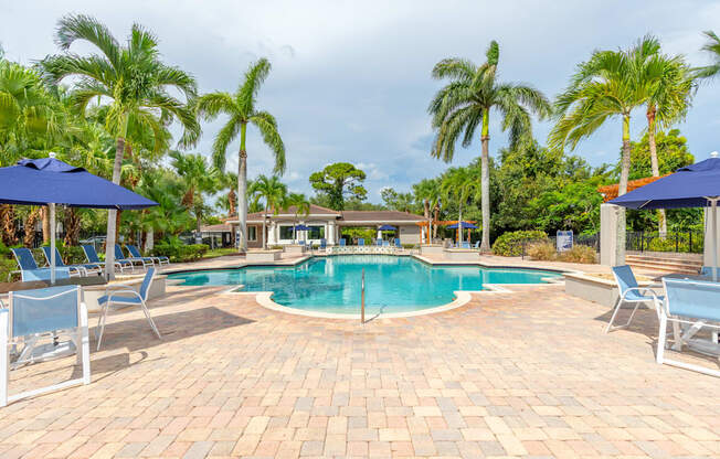 a large swimming pool with lounge chairs and umbrellas at Heritage Bay, Jensen Beach, 34957