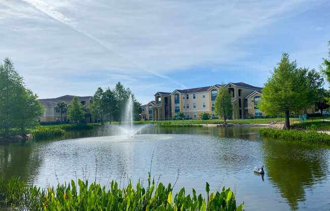 View of lake with fountain in the middle and building exteriors in the background