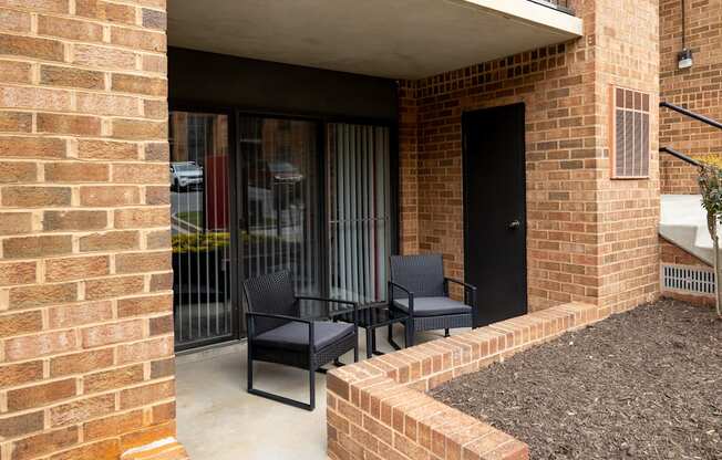 a patio with two chairs and a table outside of a building