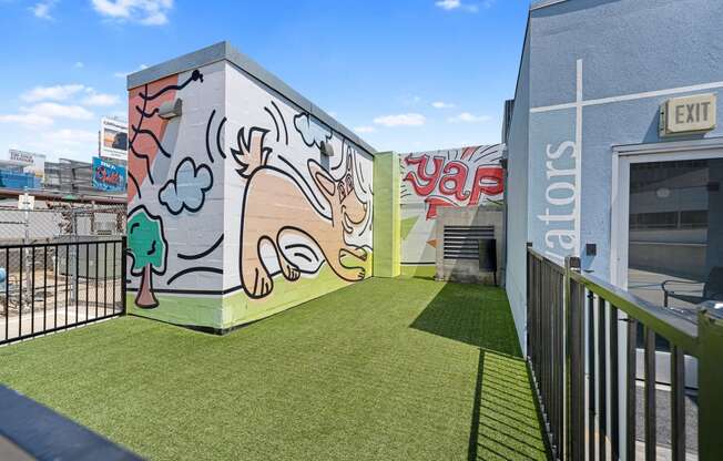 Turf dog park with mural on side of building