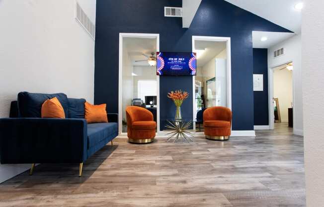 a lobby with blue walls and orange chairs and a blue couch