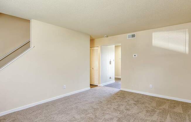 A room with a carpeted floor and a staircase leading to another room.