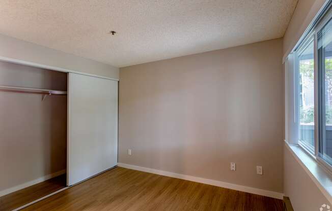 an empty bedroom with a closet and a window
