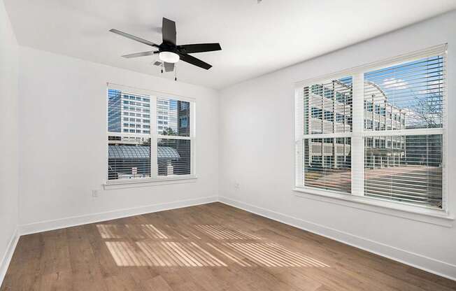 A room with a ceiling fan and two windows.