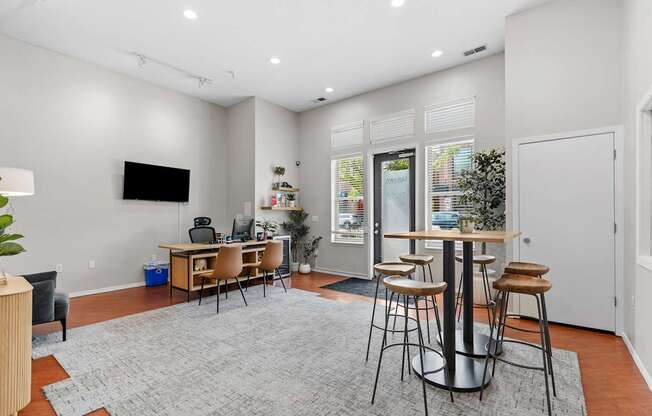 A modern living room with a grey rug and a television on the wall.