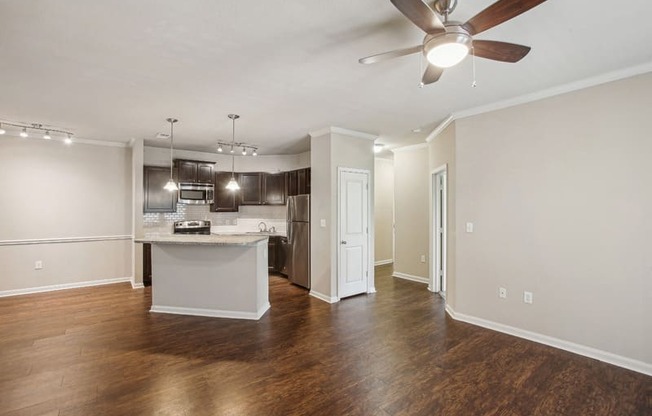an empty living room and kitchen with a ceiling fan