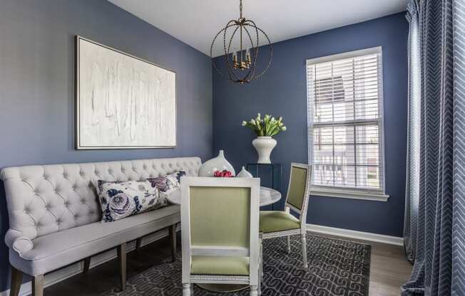 a dining room with blue walls and a white couch and a table with two chairs