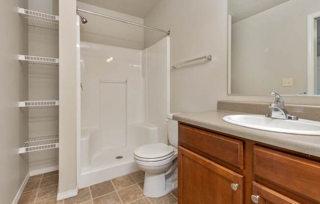 A white toilet sits in a bathroom next to a sink and a walk-in shower.