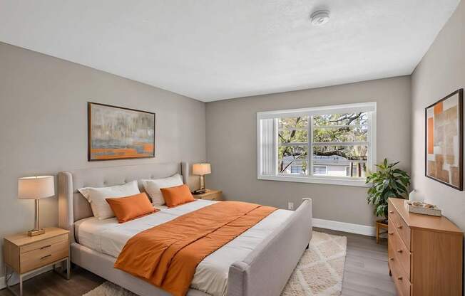 A bedroom with a bed, nightstand, and window.