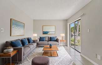 A living room with a grey couch, a coffee table, and a painting on the wall.