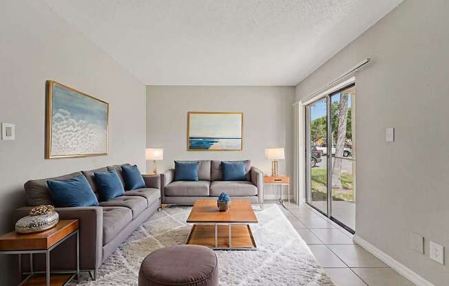 A living room with a grey couch, a coffee table, and a painting on the wall.