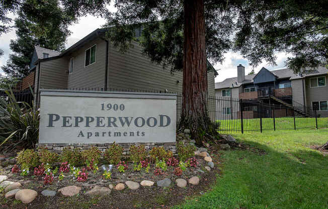 A sign for Pepperwood Apartments is in front of a tree at Pepperwood Apartments, California, 95661