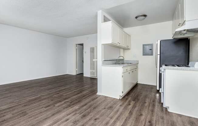 an empty kitchen and living room with a hard wood floor