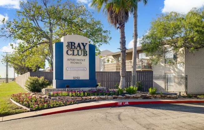 The Bay Club Apartment Homes sign is blue and white.