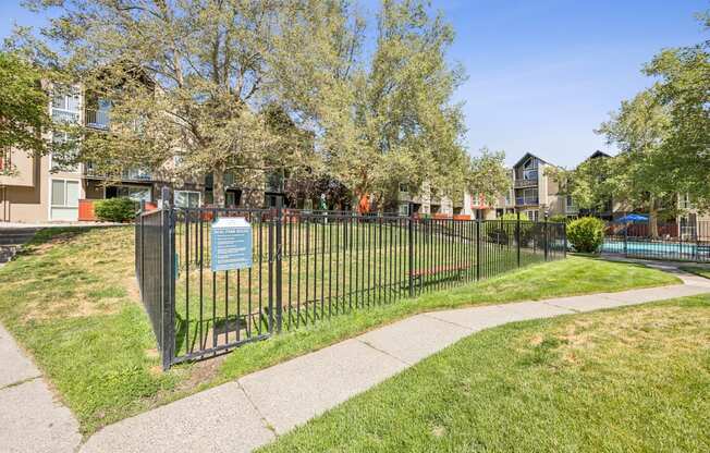 A sign is on a fence in front of a grassy area.