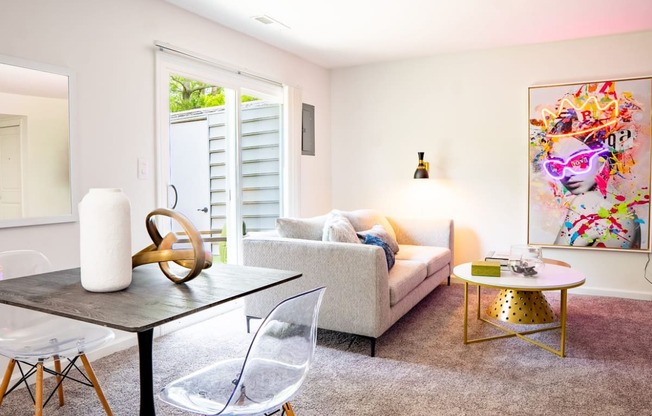 a living room with a couch table and chairs and a painting on the wall