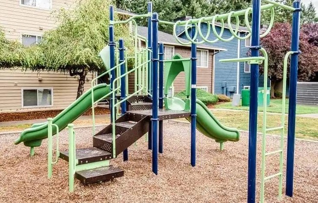 A playground with a green slide and a wooden platform at Ellyson Apartment Homes, Washington, 98444