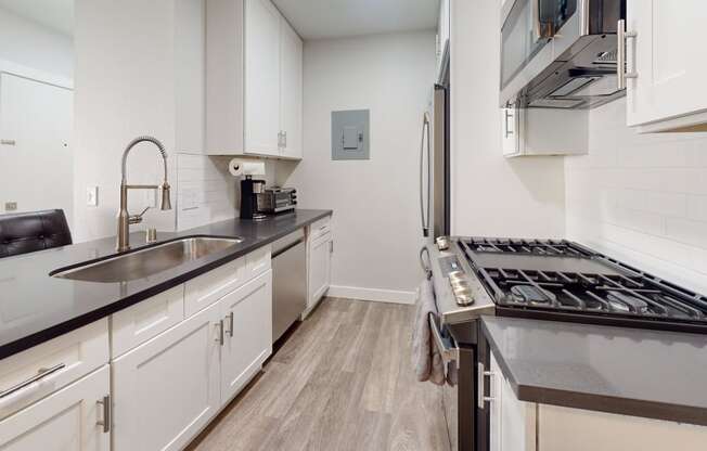 a kitchen with white cabinets and stainless steel appliances and a sink