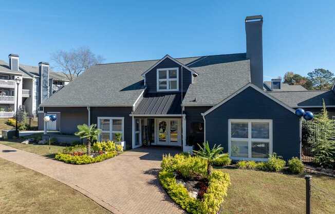 A blue house with a grey roof and a brick pathway leading to the front door.
