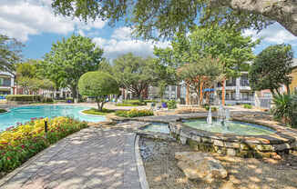 A beautiful outdoor scene with a fountain, trees, and a swimming pool.