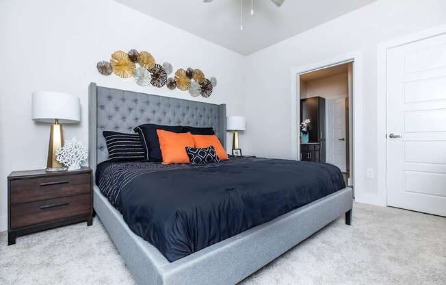 A bedroom with a bed, two lamps, and a ceiling fan.