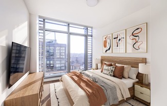 a bedroom with a large window and a bed with a wooden headboard