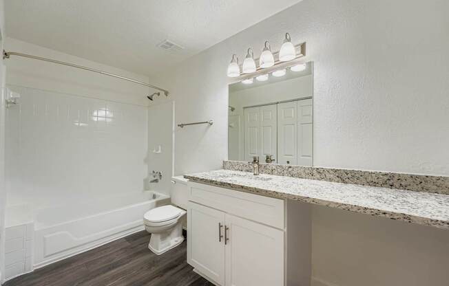 A white bathroom with a toilet, sink, and mirror.