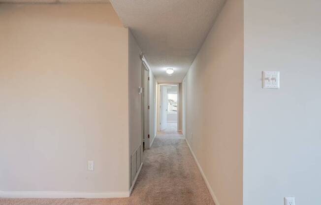 A long hallway with a carpeted floor and white walls.