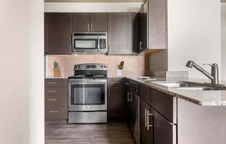 A modern kitchen with dark brown cabinets and stainless steel appliances.