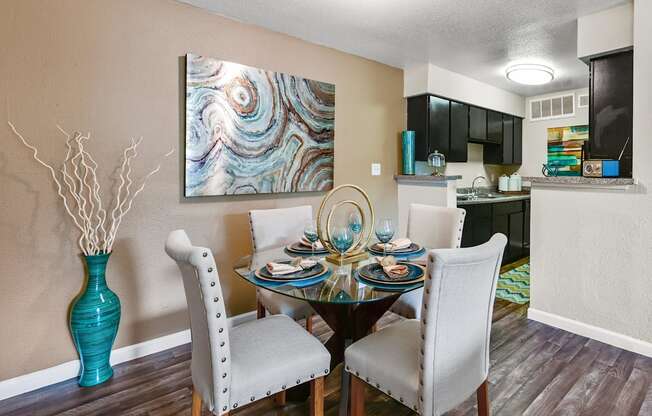 a dining room with a table and chairs and a kitchen in the background