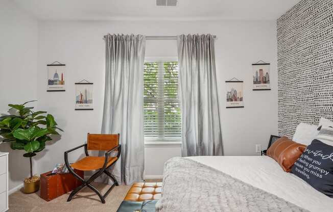 a bedroom with a bed and a window with curtains and a chair