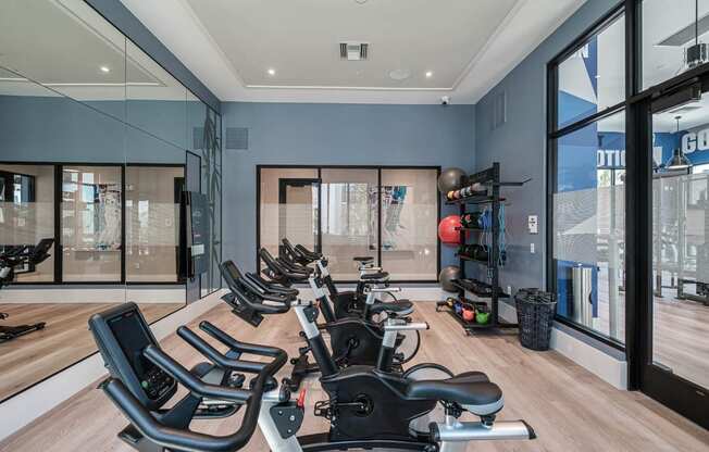 a home gym with a row of chairs in front of windows at Altis Santa Barbara, Florida