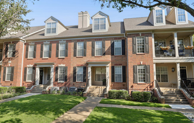 A row of red brick houses with green lawns in front.