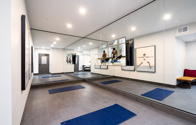a yoga room with mirrors and blue yoga mats