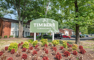 a sign that says timbers townhomes in front of a garden