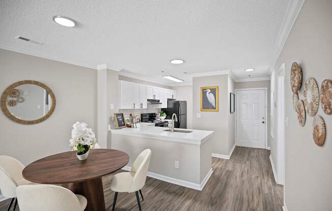 A kitchen with a table and chairs in the foreground and a sink in the background.