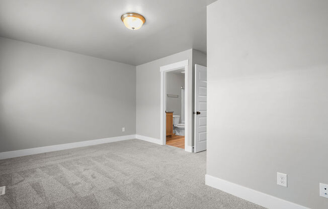 a bedroom with a carpeted floor and a door to a bathroom
