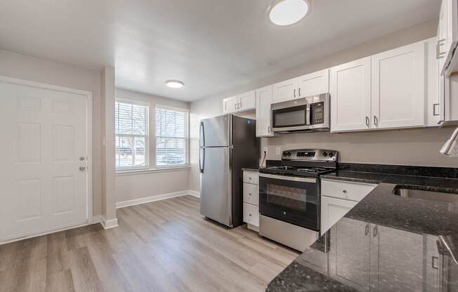 A kitchen with white cabinets and a black countertop.