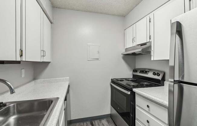 A kitchen with a stove, sink, and cabinets.